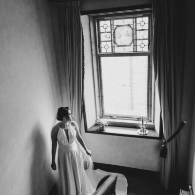 Bride standing on a landing looking out of a window