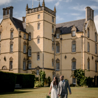 Couple walking with mansion house and Scottish flag behind them