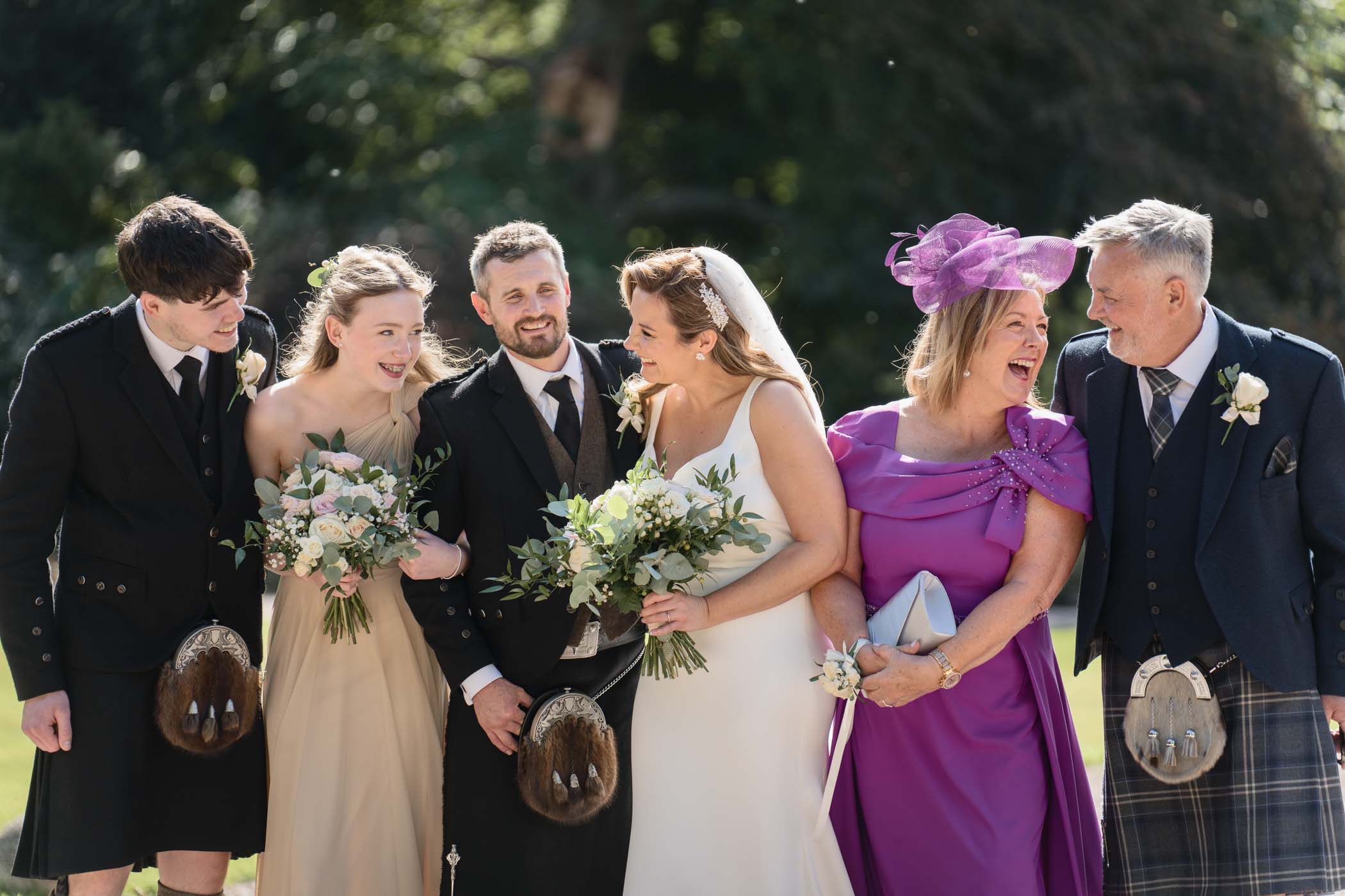 Family photo at a wedding with everyone smiling and looking at each other