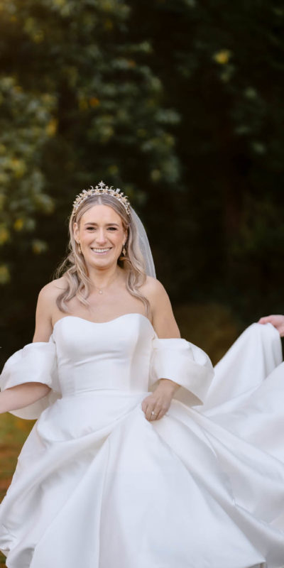Bride smiling as groom holds the train of her dress