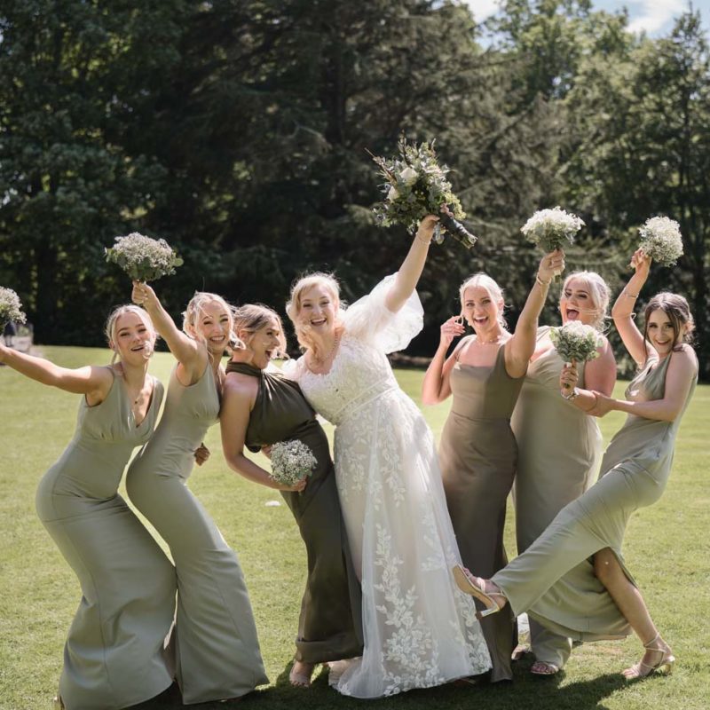 Bride and bridesmaids laughing and waving their arms in the air