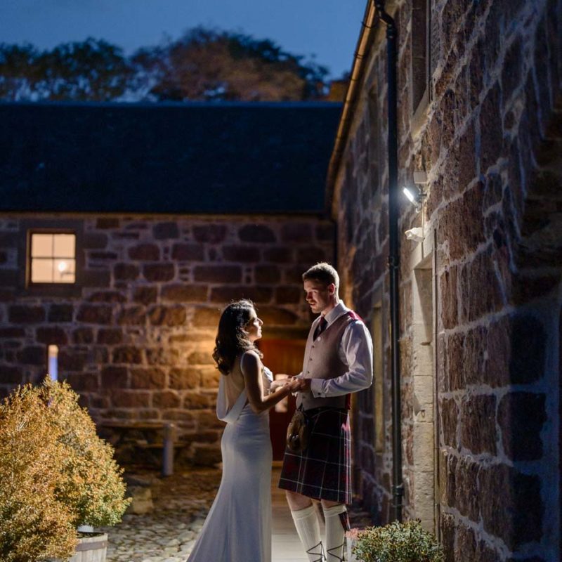 Couple standing beside a stone building at blue hour