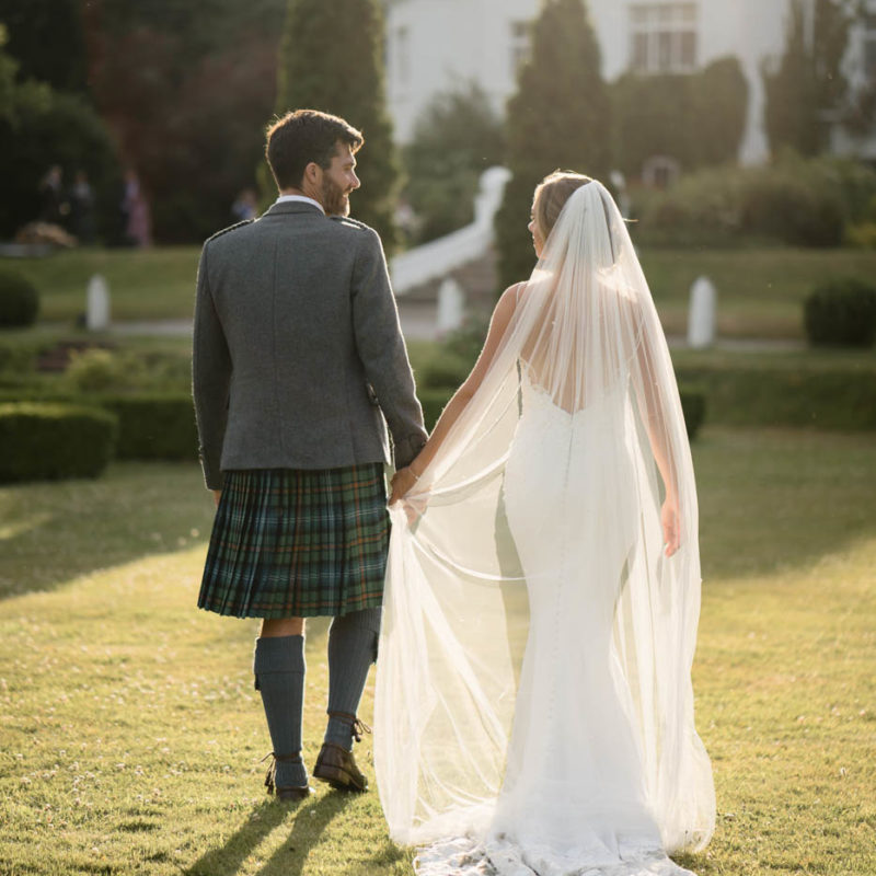 Bride and groom walking into sunset at Achnagairn Castle