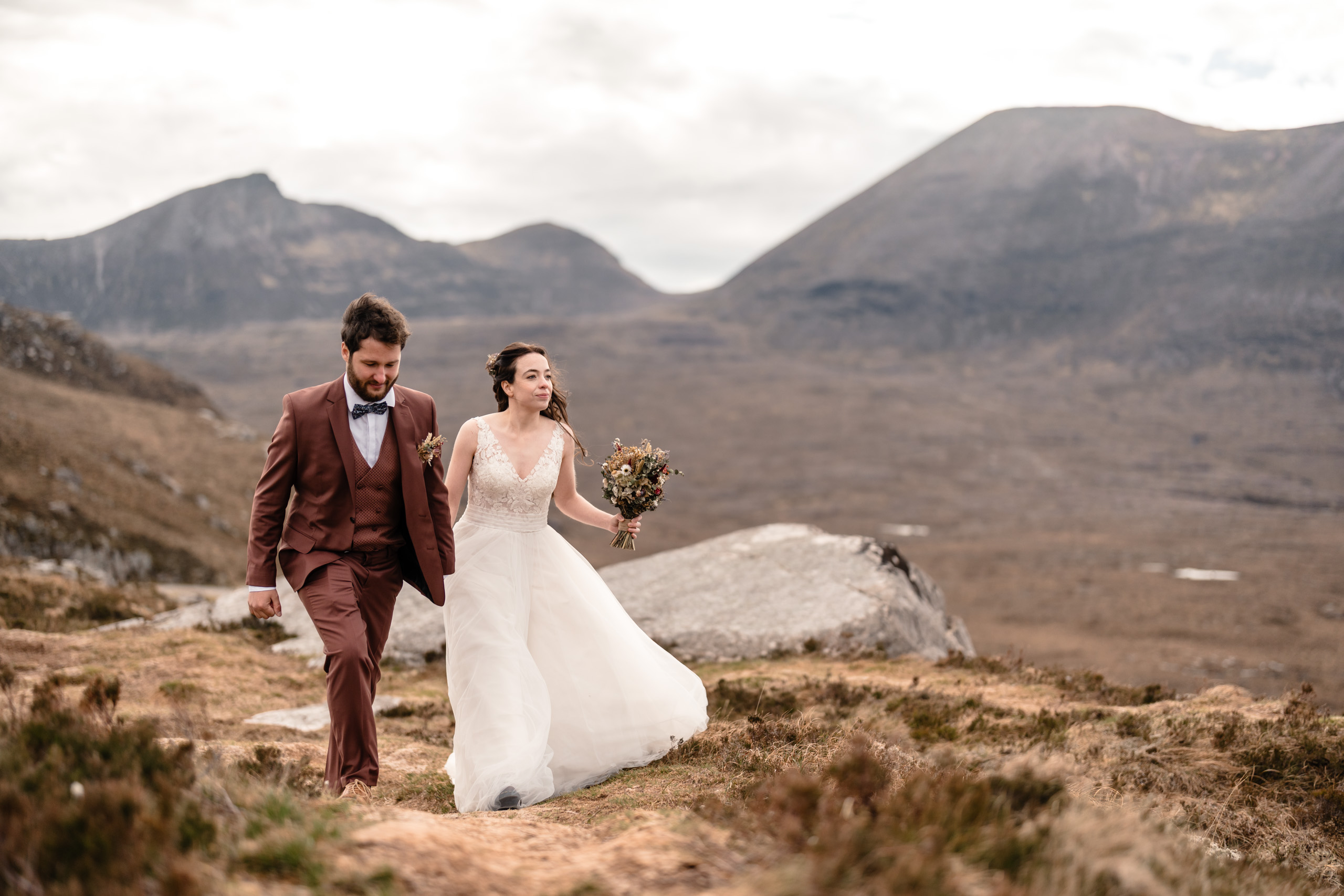 Newlyweds walking along a scenic Scottish mountain path