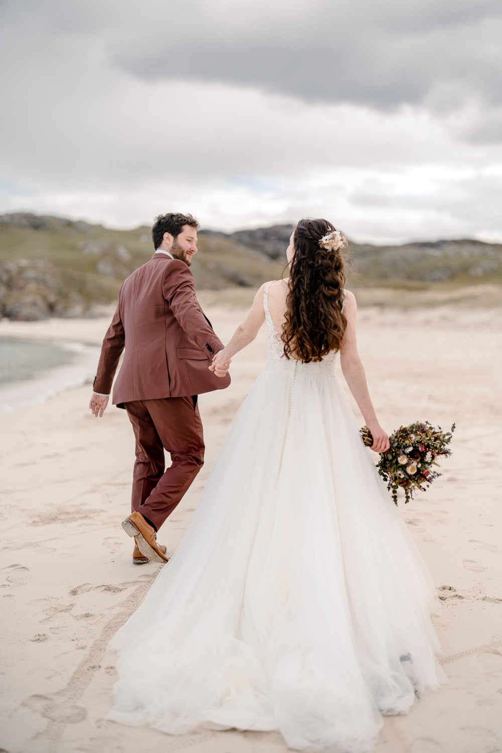 Couple walking hand in hand away on a scenic Scottish beach