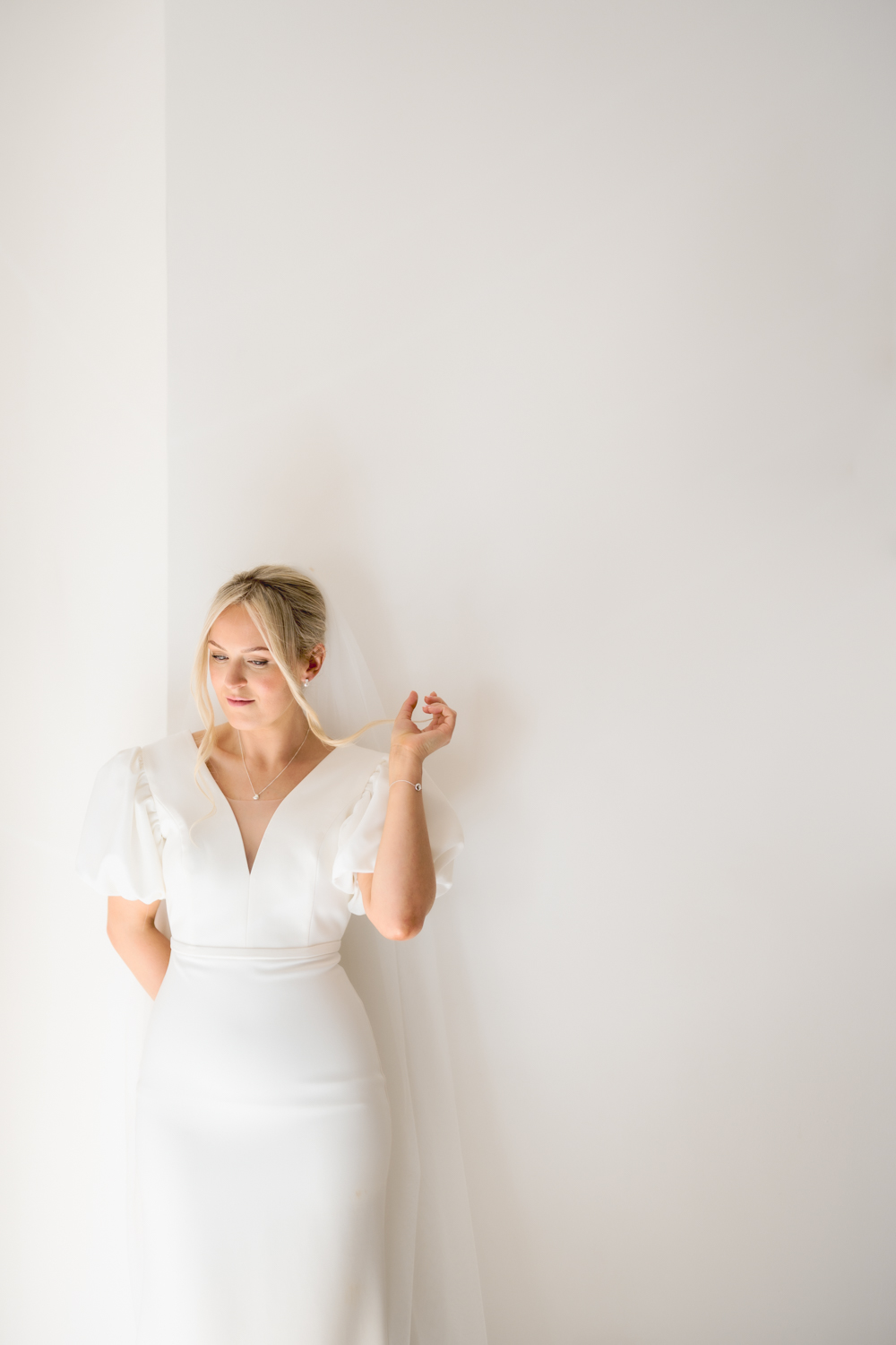 Bridal portrait of bride standing against a white wall