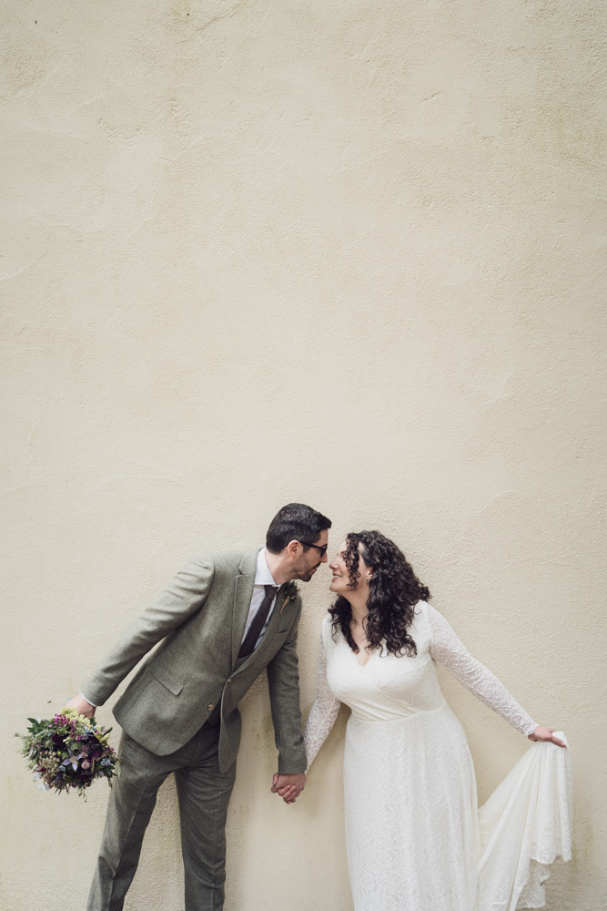 Bride and groom posing in front of a wall