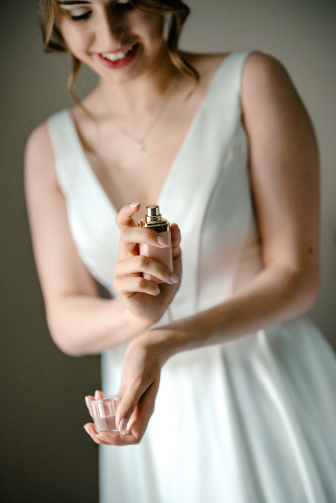 Bride’s hands delicately holding a perfume bottle, showcasing wedding details