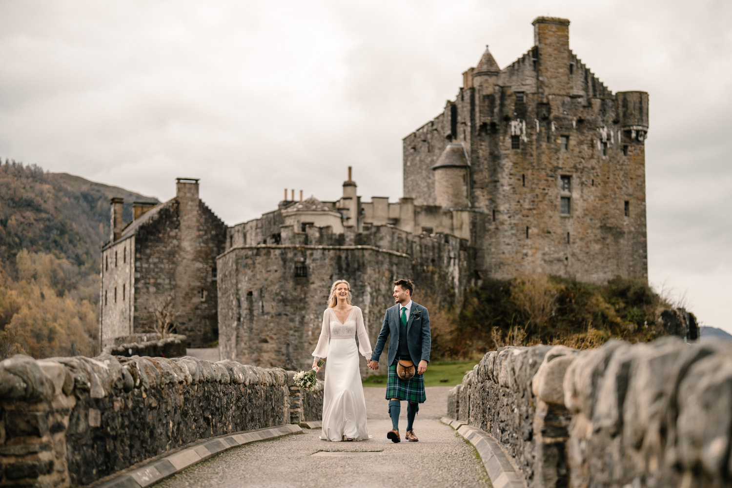 Bride and groom laughing with Eilean Donan Castle behind them