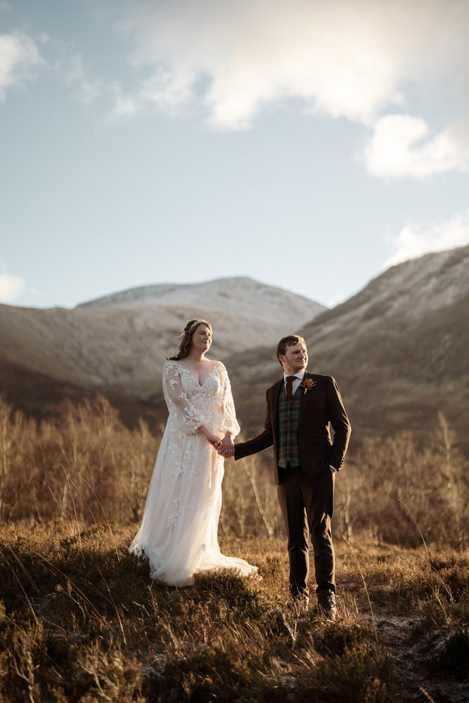 Newlyweds standing together on Scottish moorland with Glen Etive’s rugged hills in the background