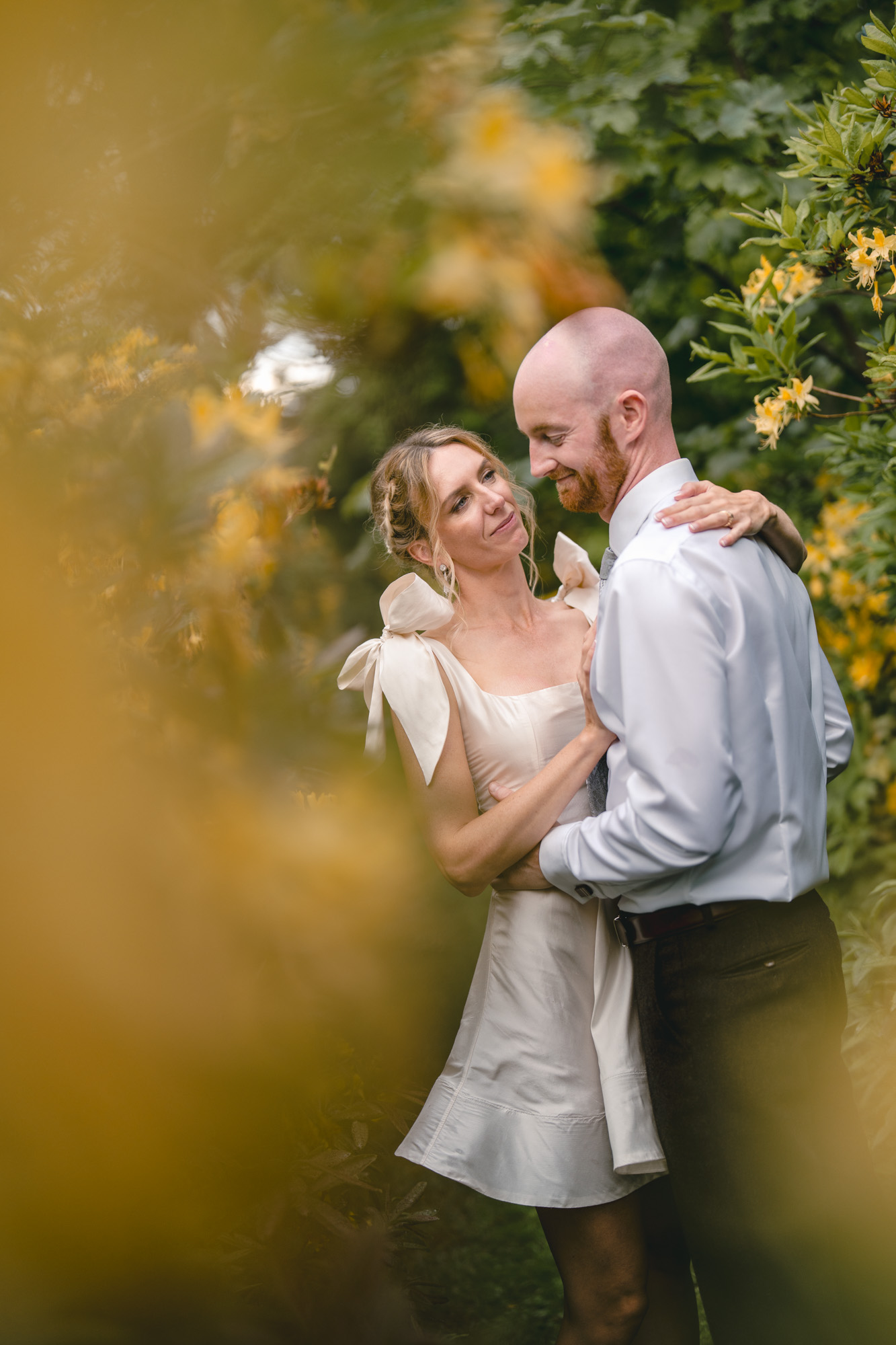 Couple sharing an intimate moment in a walled garden surrounded by yellow flowers