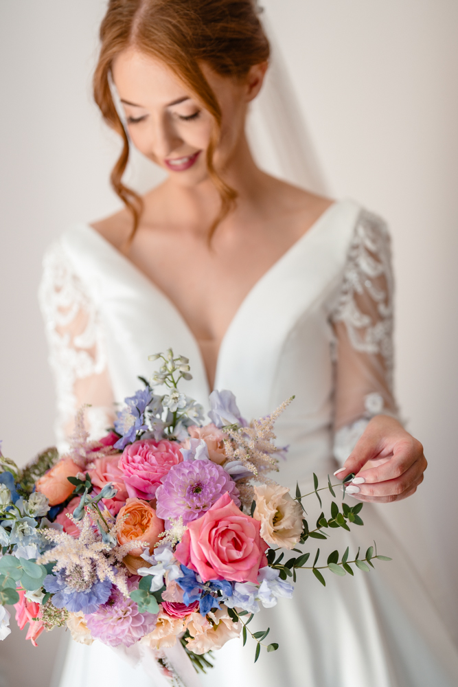 Bridal portrait of the bride holding bright pink flowers and looking down at them