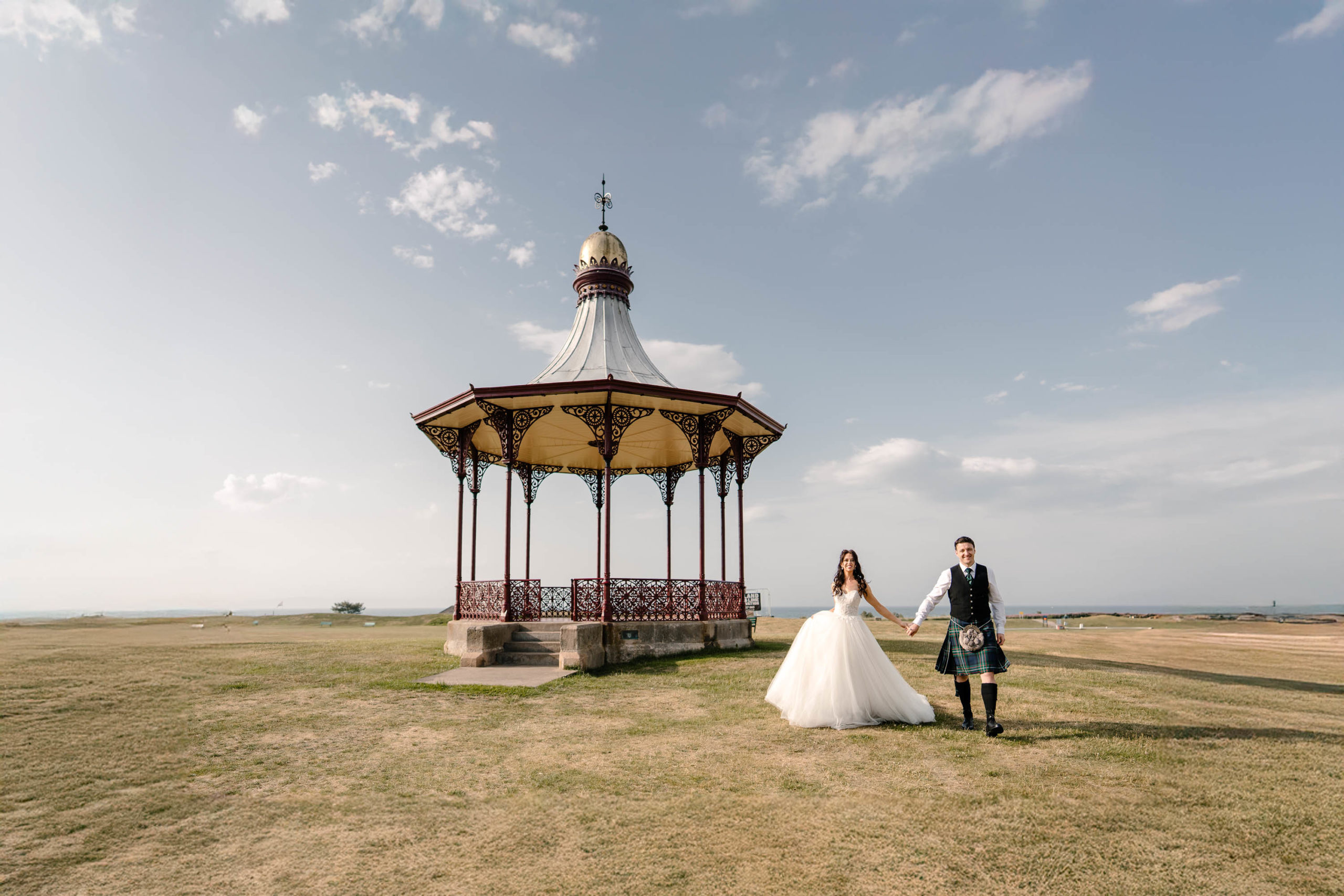Newlyweds posing in front of the Bandstand in Nairn on a summer evening