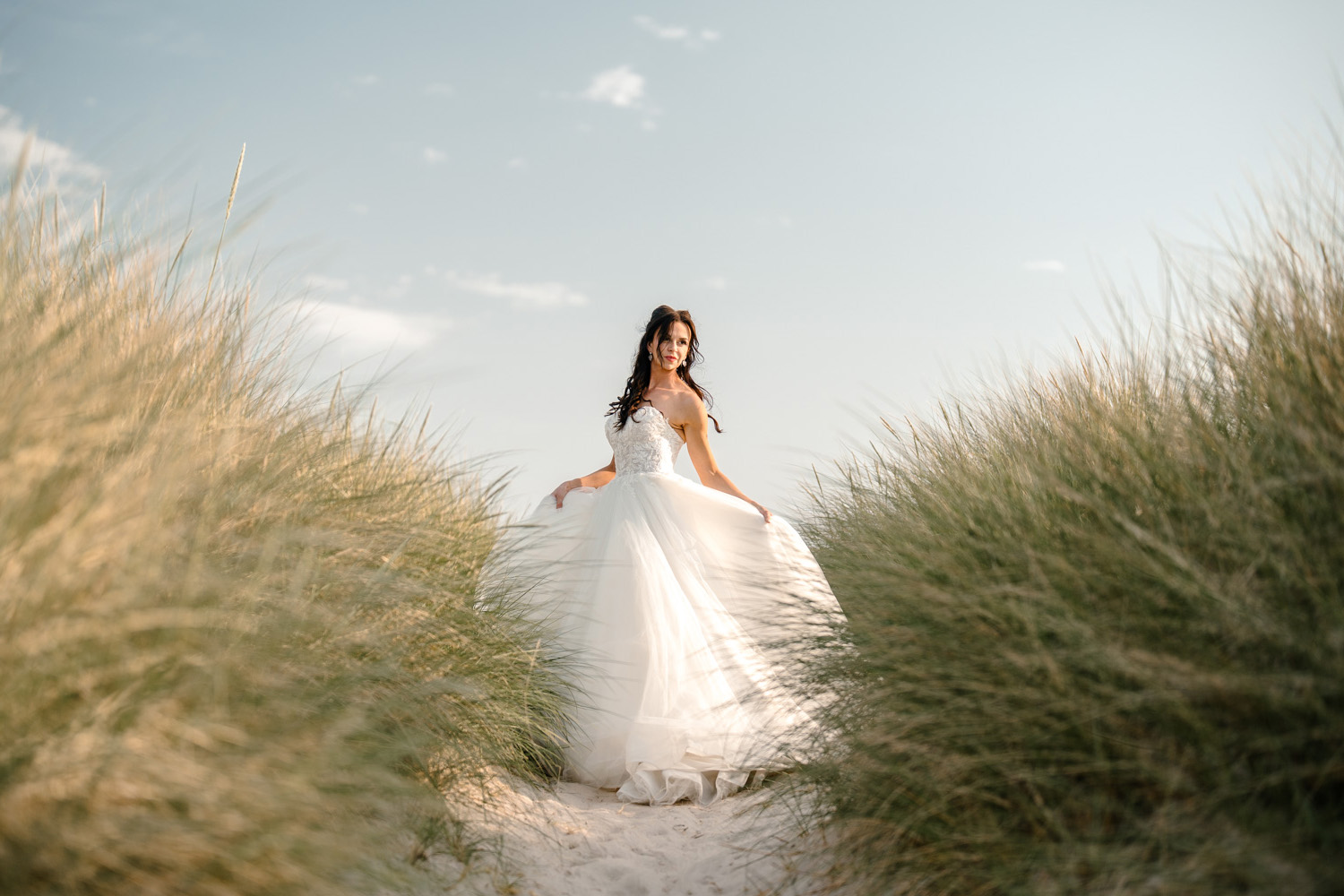 Stunning bride posing on beach with tall dune grass