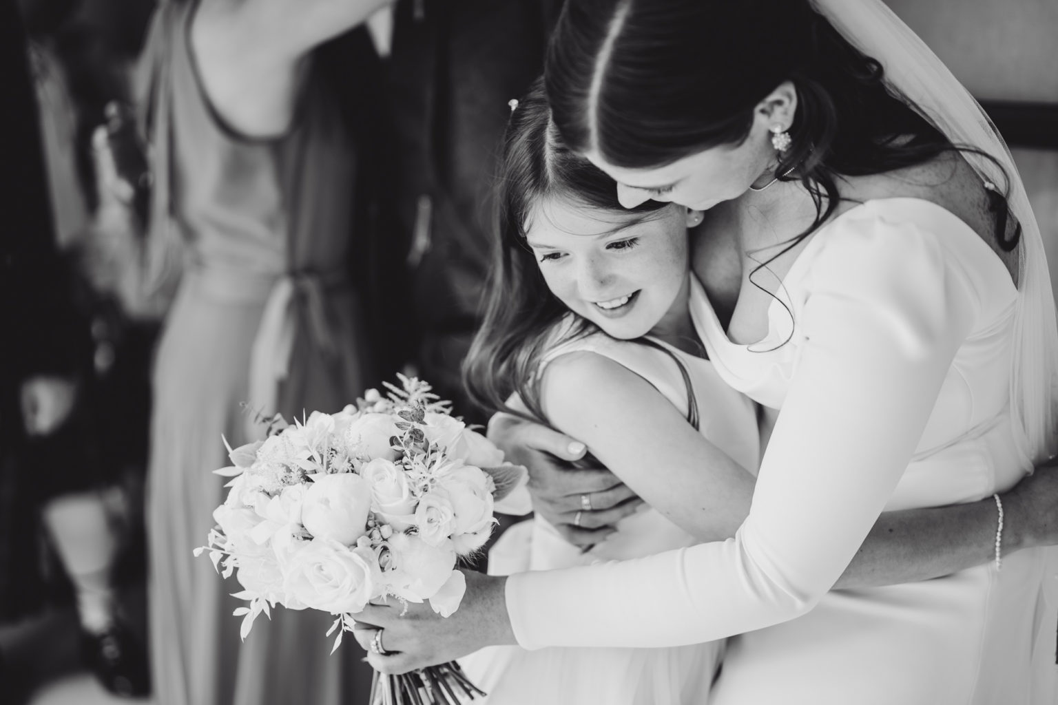 Monochrome image showing bride warmly hugging the flower girl