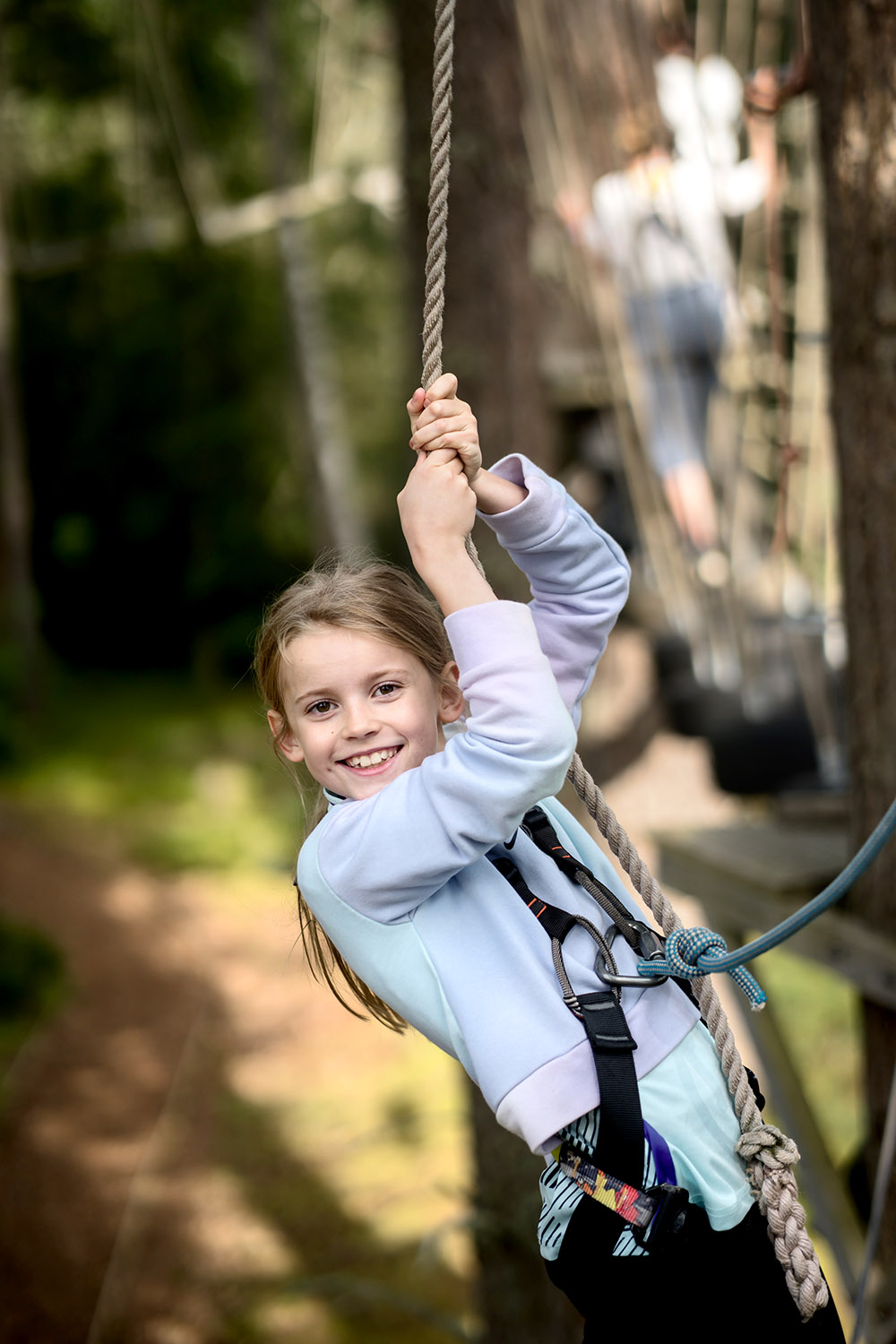 Smiling girl taking part in a tree climbing trail