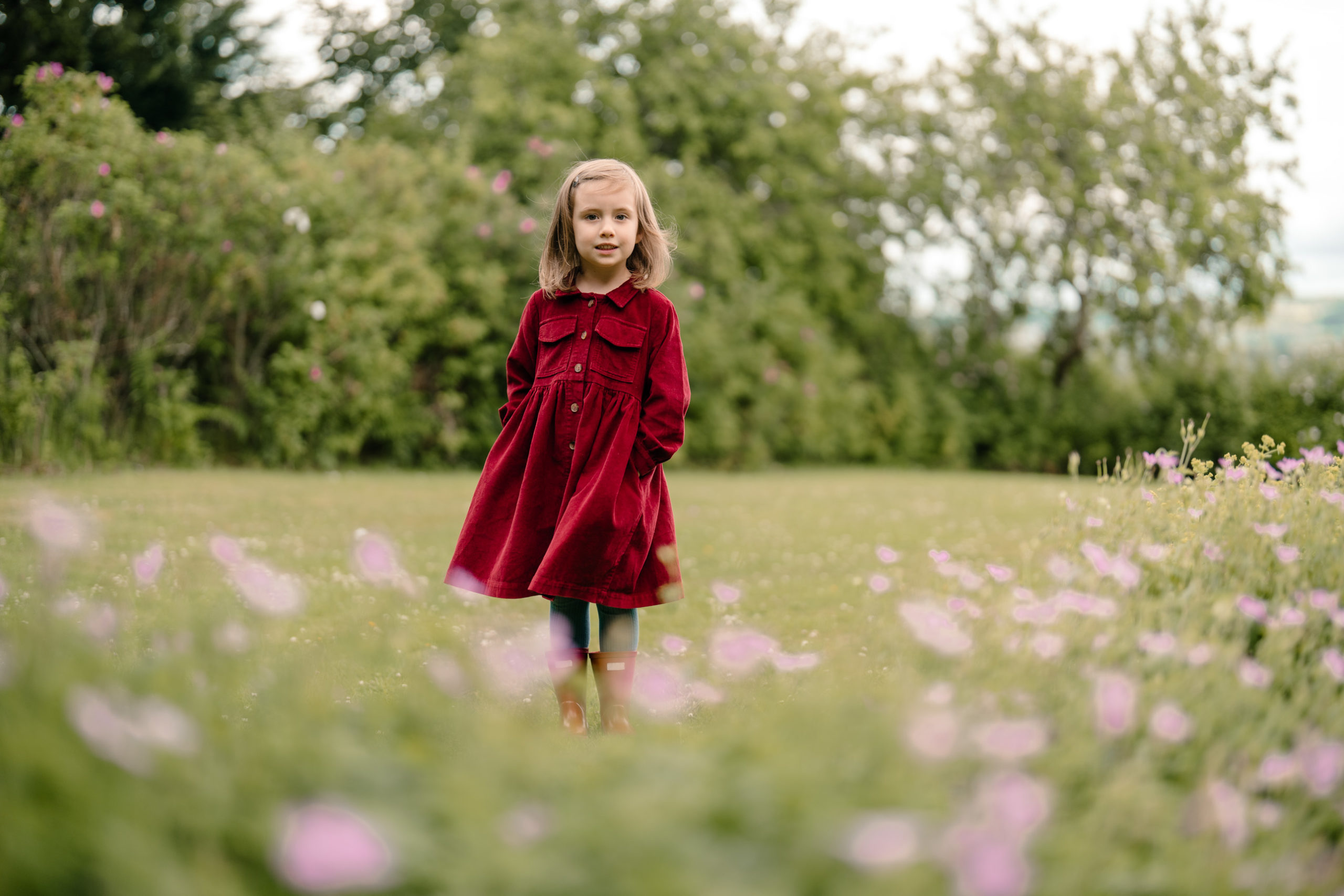 Child standing among blooming flowers.