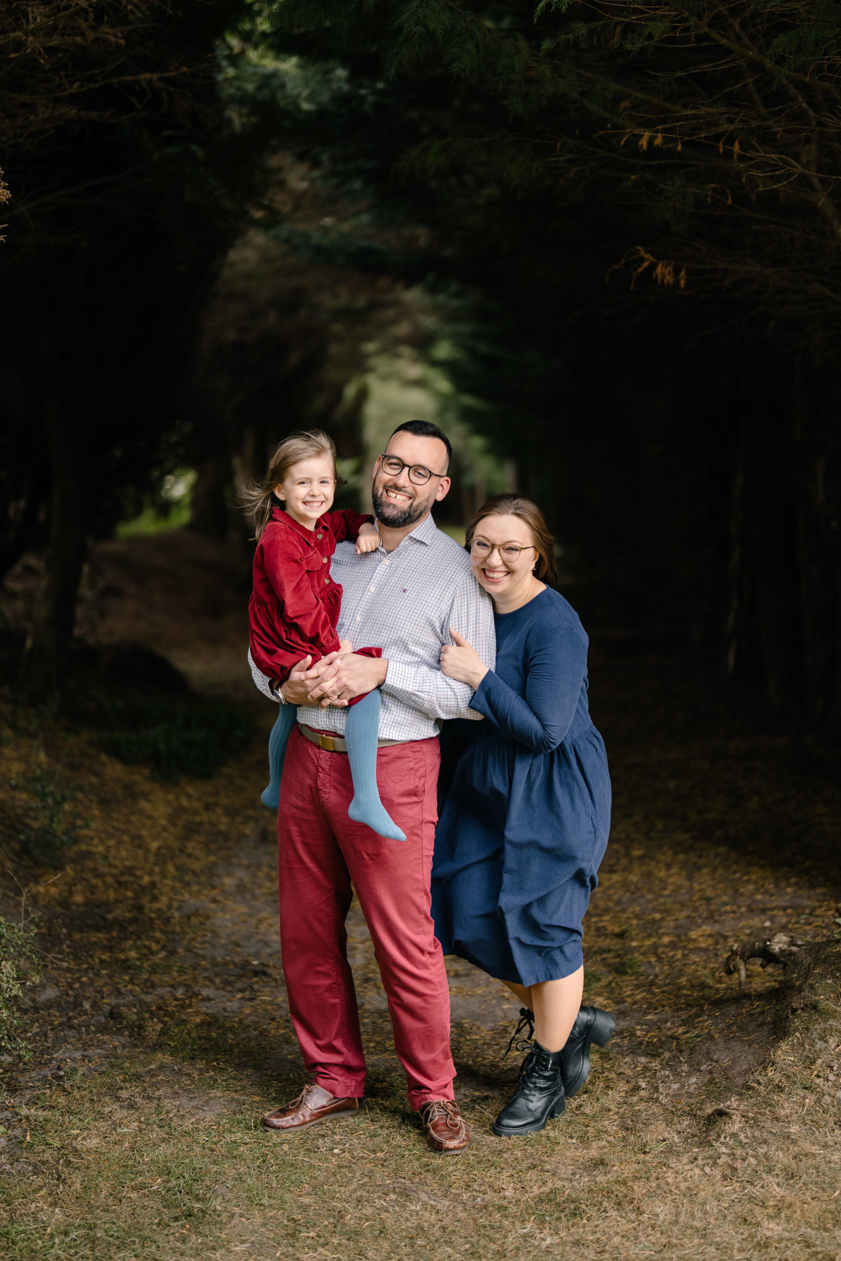 Parents and children posing on a tree-lined woodland trail.