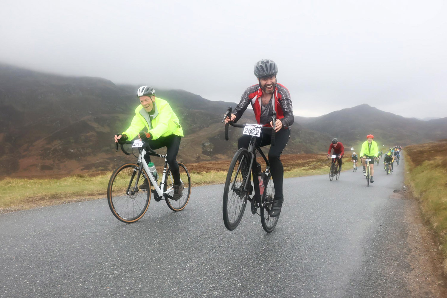 Laughing cyclist popping a wheelie while riding with a cycling group