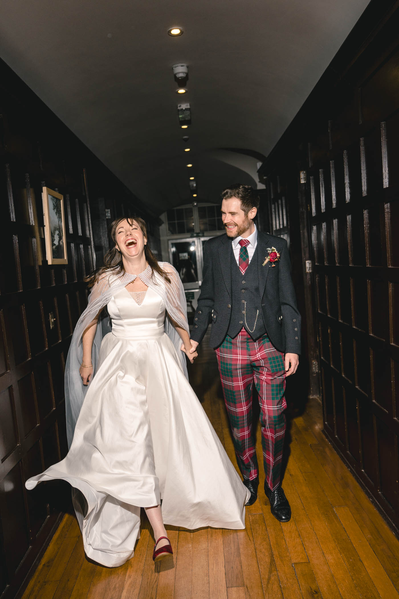 Bride and groom sharing a laugh while walking through a castle hallway