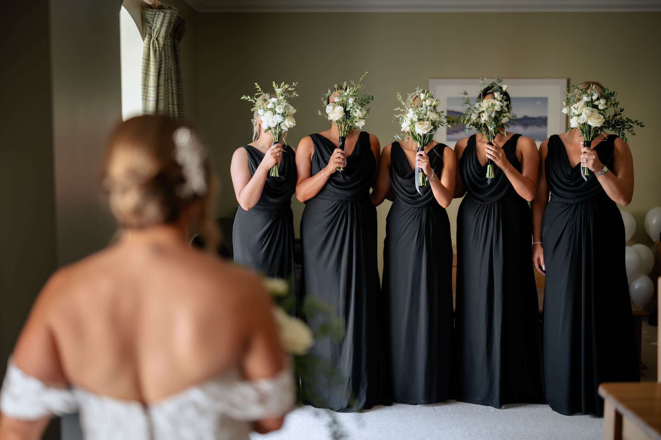 Bridal party hiding their faces behind bouquets before the bride’s reveal