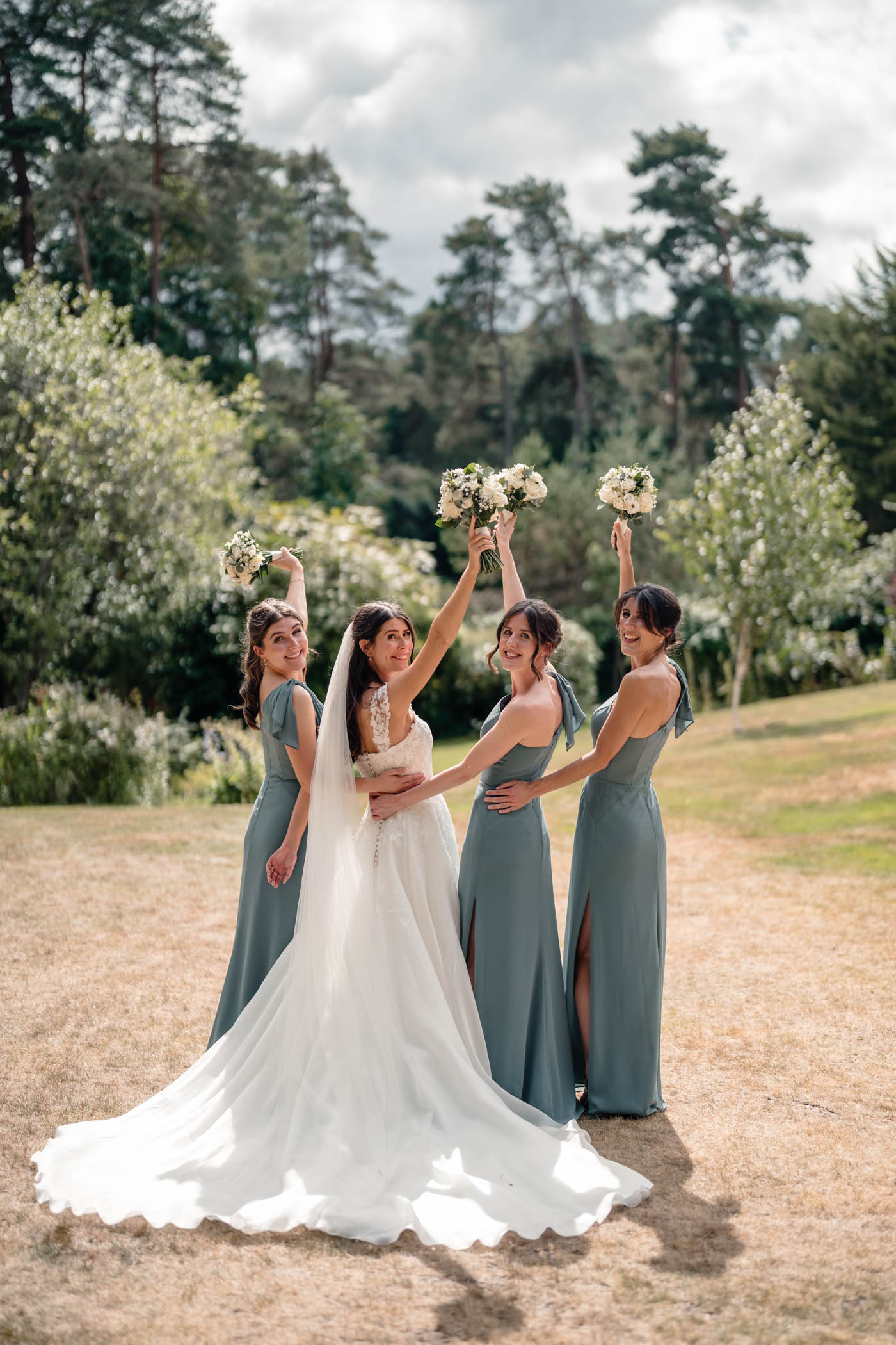Bride and bridesmaids celebrating together, holding bouquets high