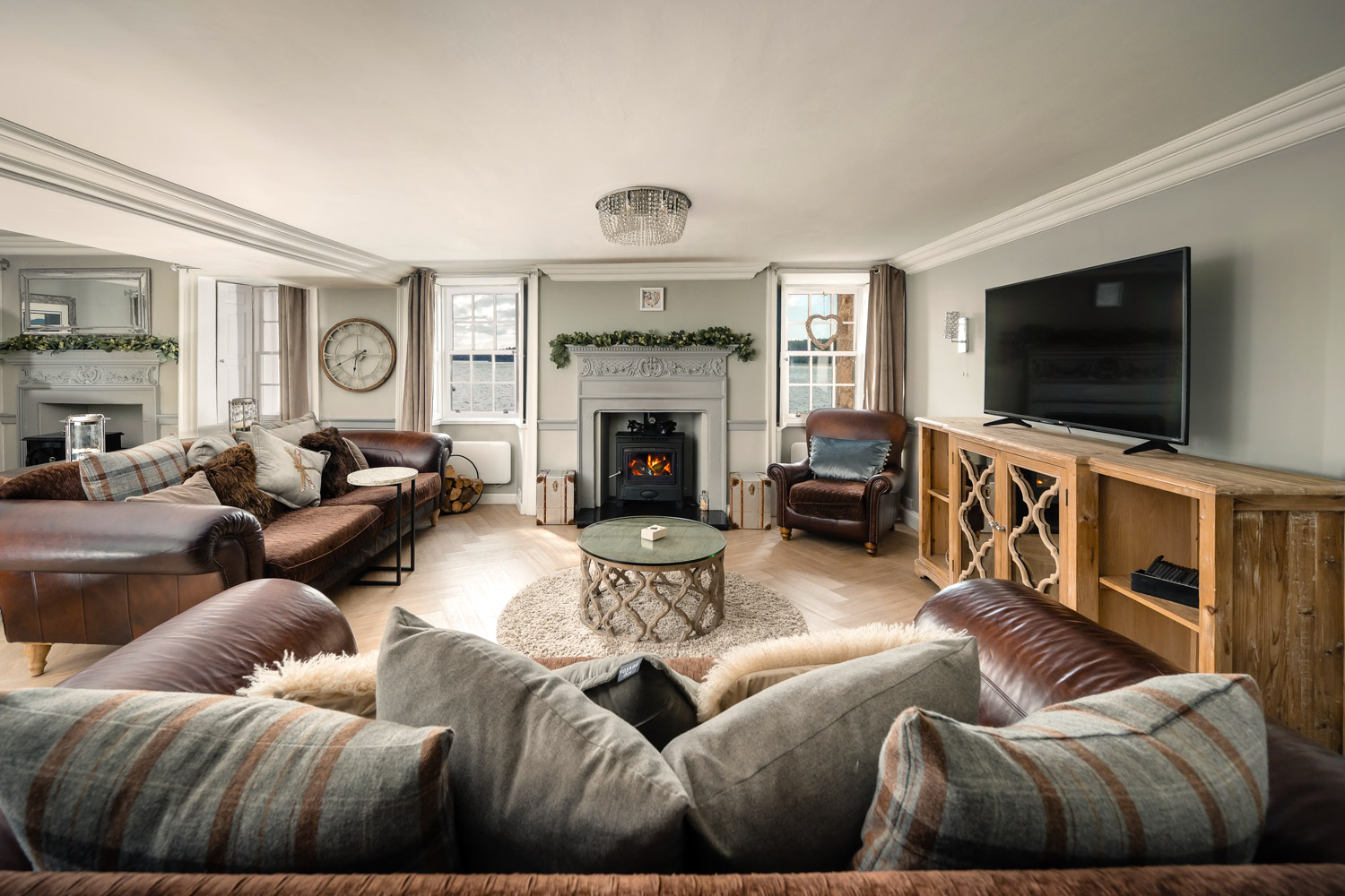 Cosy living room with chunky, comfortable sofas arranged around a warm fireplace, creating a welcoming and relaxing atmosphere.