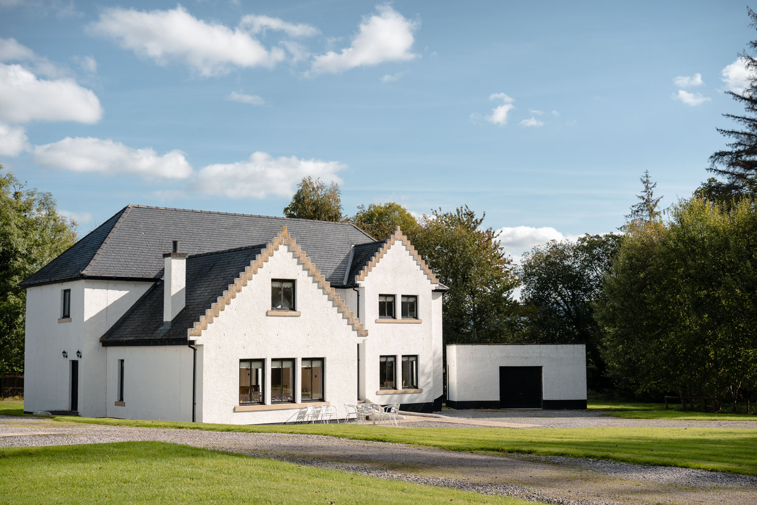 Exterior of a property on a sunny day beneath a clear blue sky, with bright natural light highlighting the building and surrounding grounds.