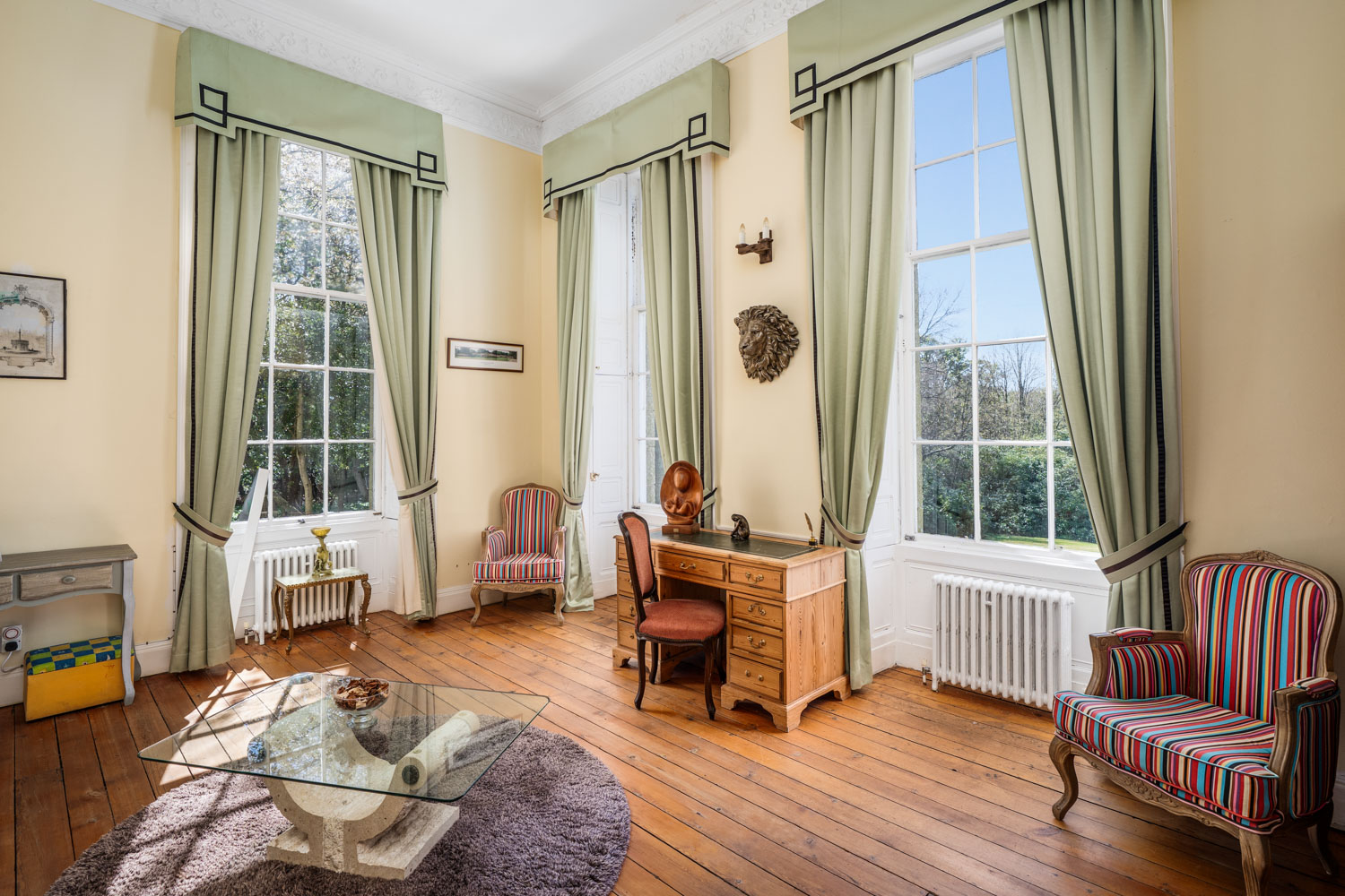 Landscape view of an elegant interior with high ceilings and a traditional cast-iron radiator, highlighting the property's period features and sense of space.