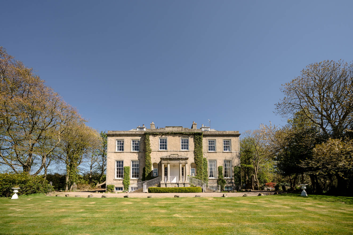 Exterior view of Cortes House on a sunny day, with bright natural light illuminating the historic building and its surrounding grounds.