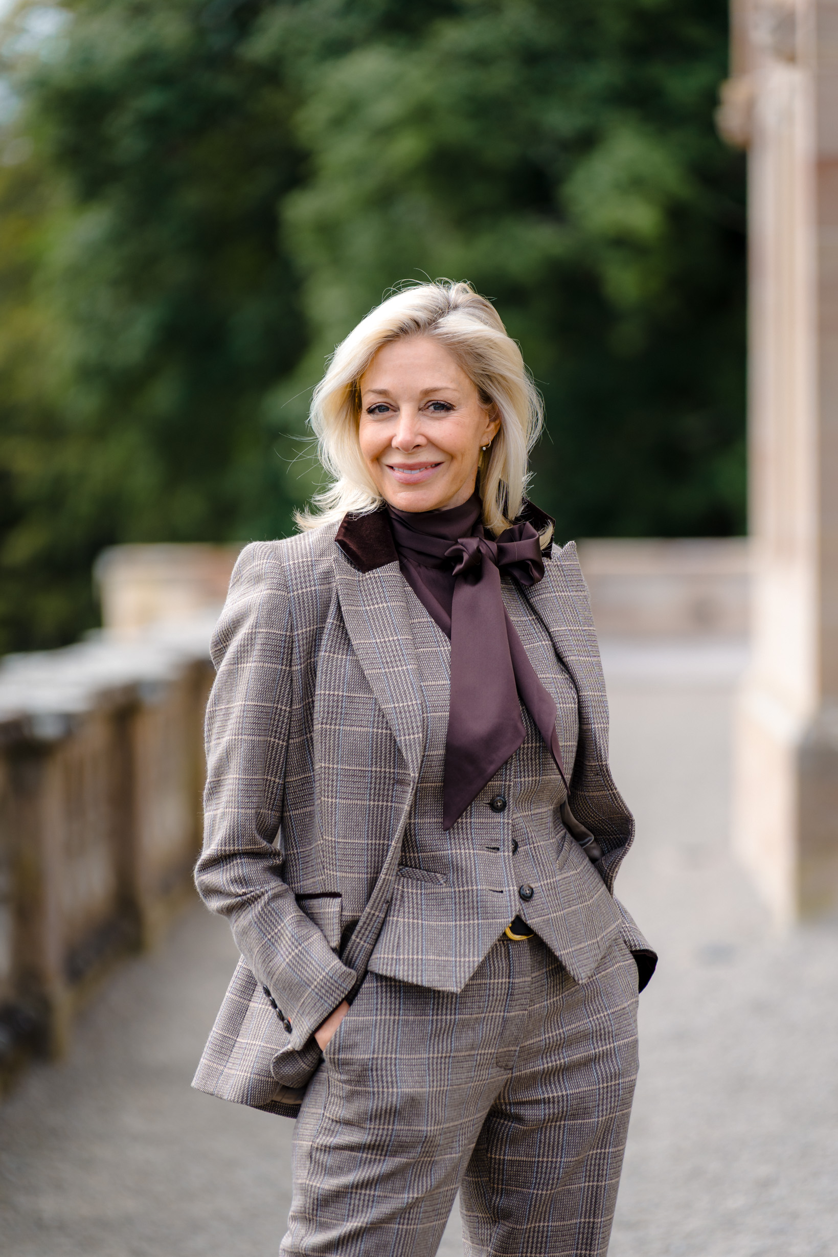 Confident woman smiling towards the camera while wearing country-style clothing, posing outdoors in natural light.